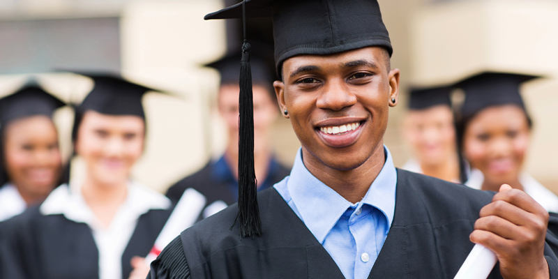 college graduates in cap and gown holding diplomas