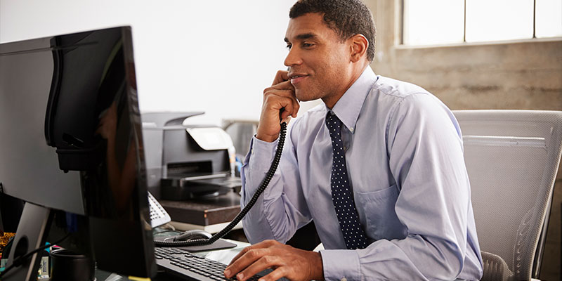 man on the phone and sitting at computer