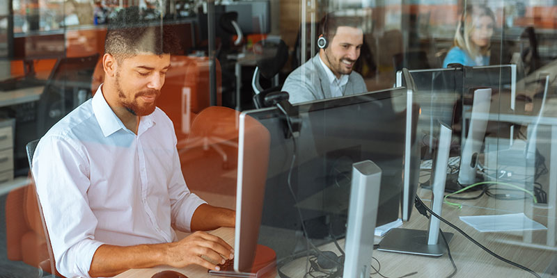 People sitting in office working on computers wearing headset