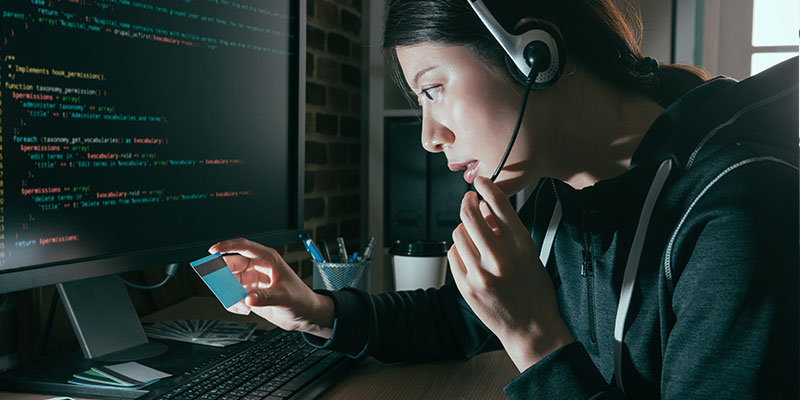 Person looking at credit card, while on computer