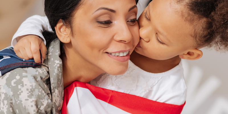 mother in military fatigues hugging daughter