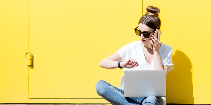 woman looking at watch with laptop on her lap