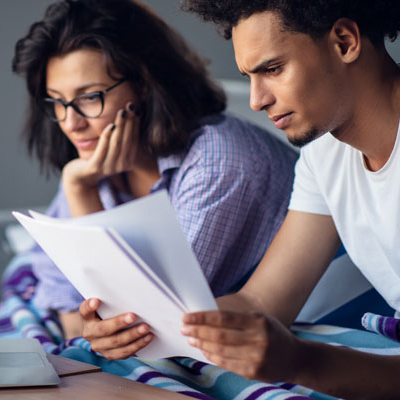 man and woman looking at document in front of laptop