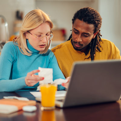 man and woman looking at document in front of laptop