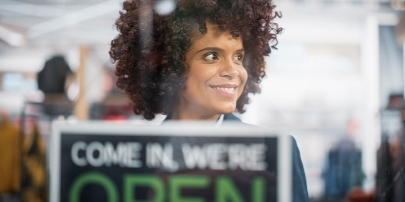 woman putting up open sign for business