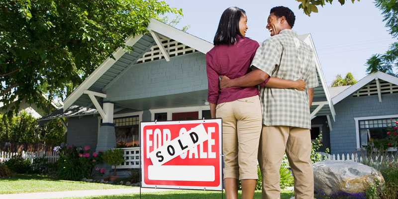 couple outside of house with sold sign